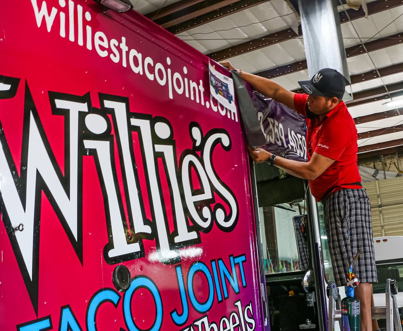 A&M Graphics installer applying vinyl to a food truck wrap